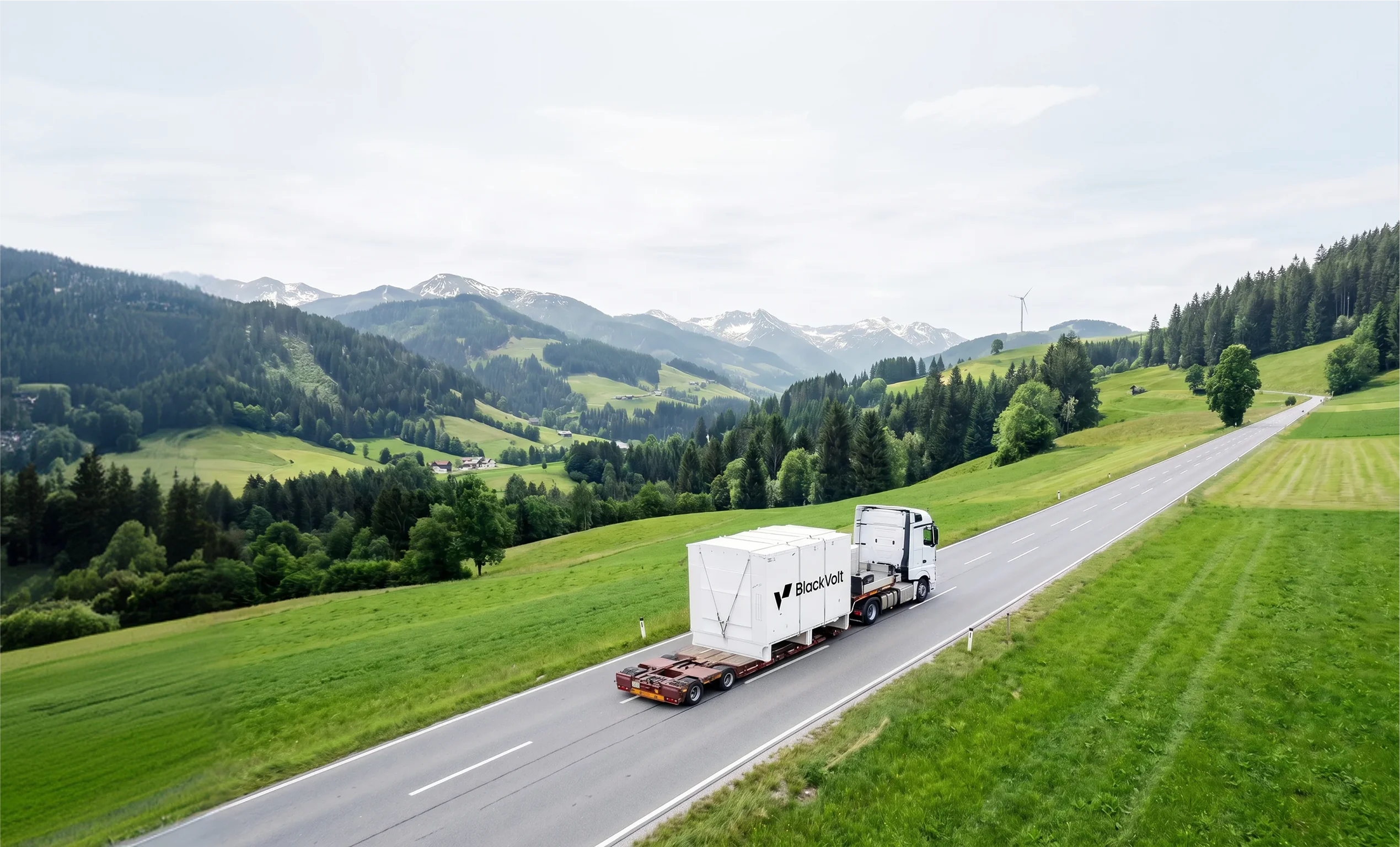 Luftaufnahme: Lastkraftwagen transportiert Blackvolt-Großbatteriespeicher-Container auf Bergstraße in Österreich